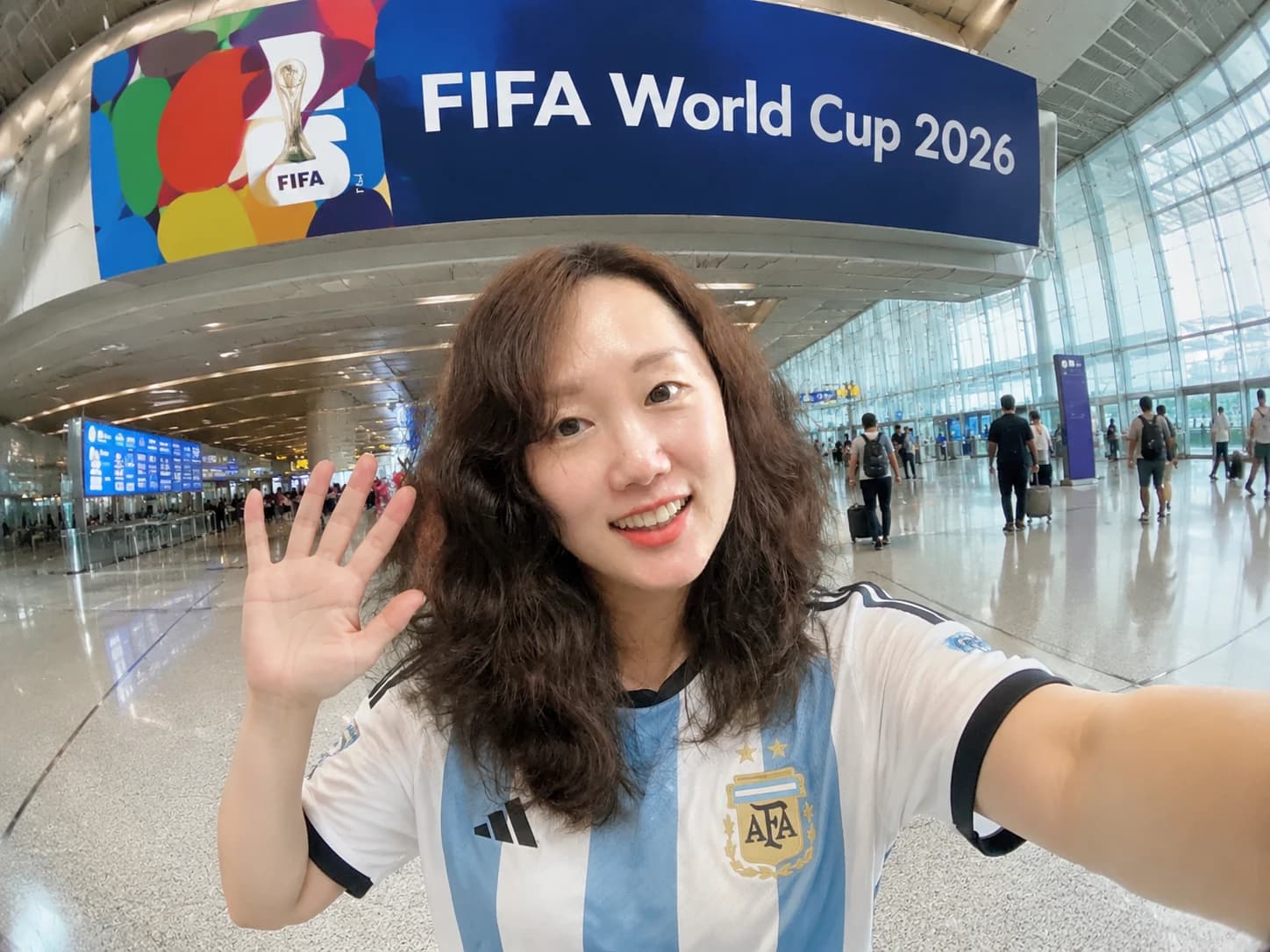 Traveler selfie inside a modern airport terminal with a World Cup 2026 banner